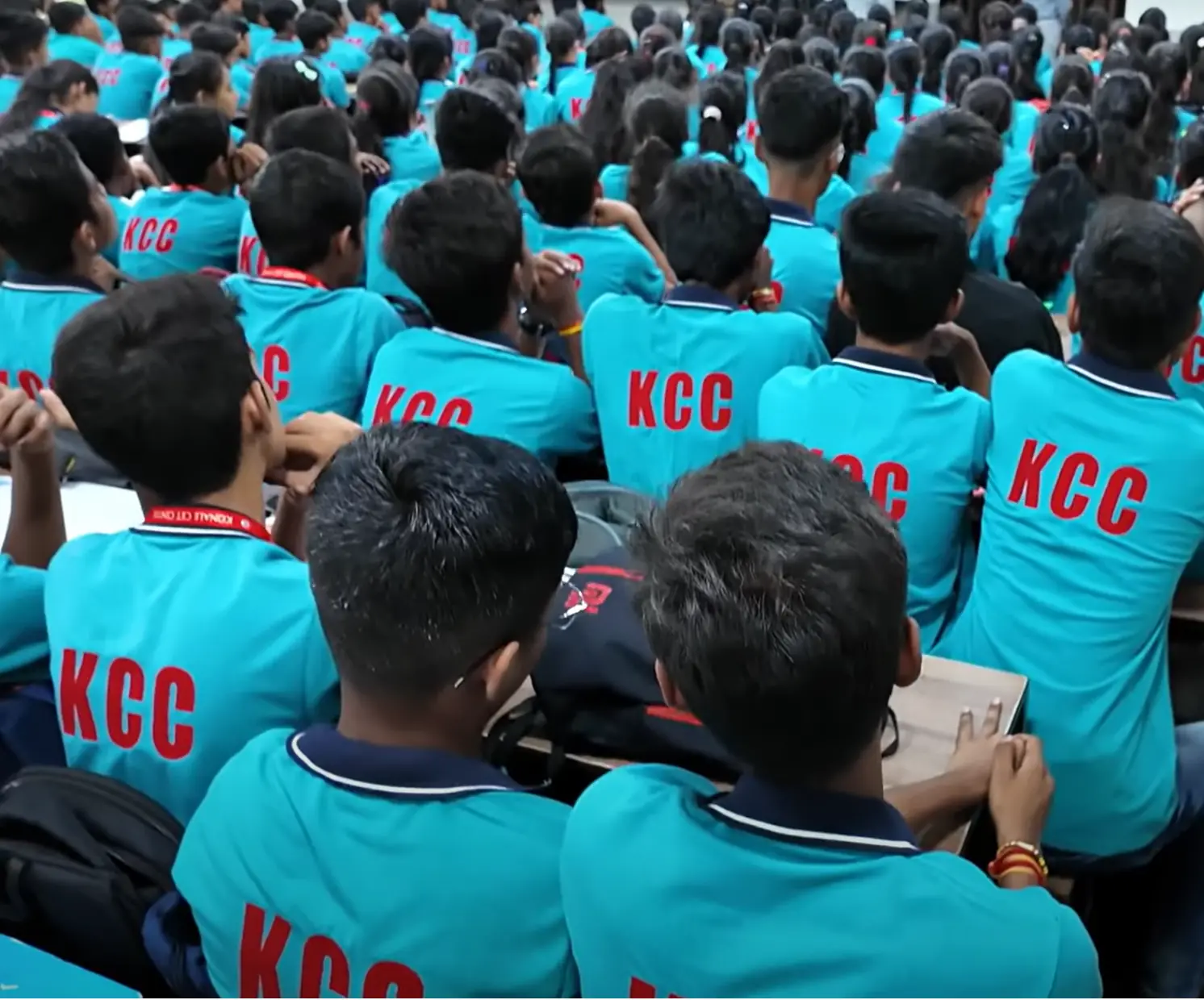 A packed hall of students in teal KCC shirts